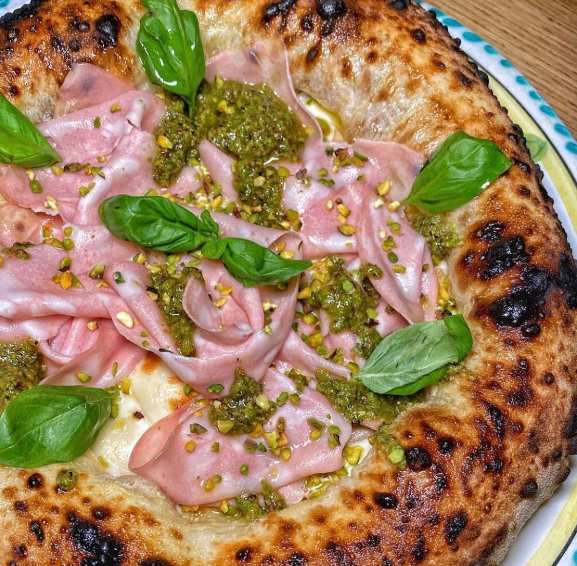 Pizza topped with mortadella, pistachios and basil
