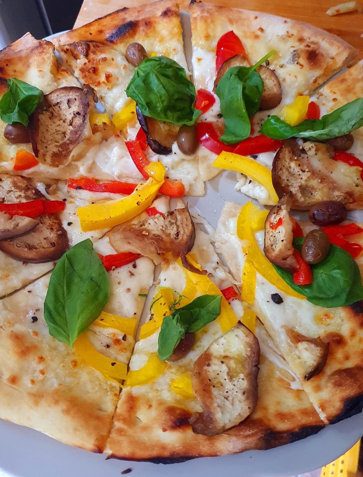Vegetable pizza with basil and colorful peppers prepared during a pizza lesson